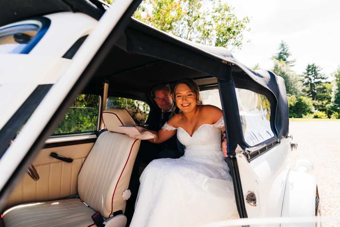 The excited Bride arriving for her wedding ceremony at Shottle Hall, Derbyshire in Bonnie, the wedding car